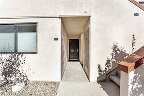 A building entrance with a door, a window, and a small outdoor area with a step leading up to the entrance. - Comfy 1BR Lakefront - Patio - Pool - (Chelan)