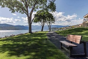 A park with a bench, trees, and a view of a lake and mountains. - Comfy 1BR Lakefront - Patio - Pool - (Chelan)