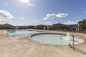 A swimming pool area with a hot tub, surrounded by buildings with a mountainous backdrop. - 3BR Riverview Townhome with shared hot tub & pools (Quincy)