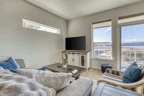 A modern living room with a sofa, a coffee table, and a television on a cabinet. - 3BR Riverview Townhome with shared hot tub & pools (Quincy)