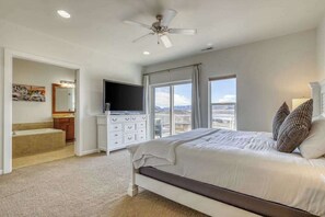 A bedroom with a bed, a television, a ceiling fan, and a large window with a view. - 3BR Riverview Townhome with shared hot tub & pools (Quincy)