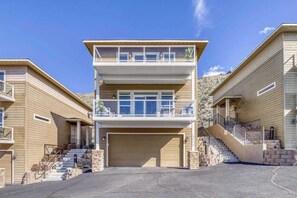 A two-story residential building with a central garage, a balcony on the upper floor, and a staircase leading to the entrance. - 3BR Riverview Townhome with shared hot tub & pools (Quincy)