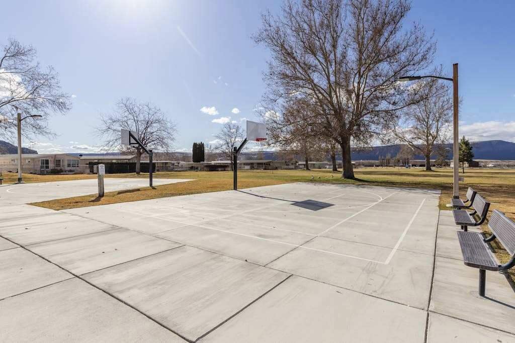 An outdoor basketball court with a bench and a basketball hoop.