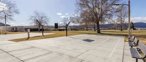 An outdoor basketball court with a bench and a basketball hoop.
