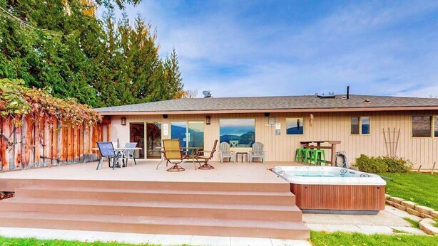 A house with a patio, outdoor seating, a hot tub, and a view of the mountains. - Peaceful 3BR Lakeview - Hot Tub - Fireplace (Manson)