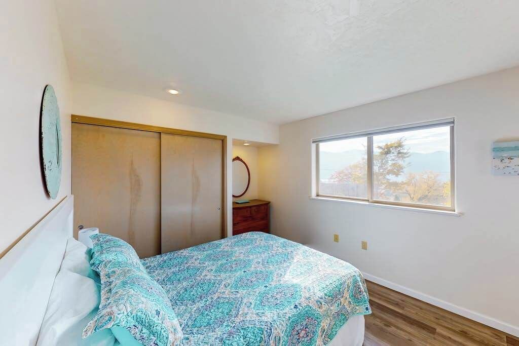 A bedroom with a bed, a window with a view, a wardrobe, and a mirror.