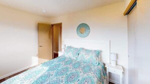 A bedroom with a bed, bedside tables, a door, and a wall-mounted light fixture. - Peaceful 3BR Lakeview - Hot Tub - Fireplace (Manson)