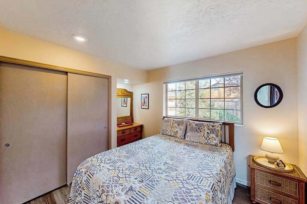 A bedroom with a bed, dresser, window, and a lamp.