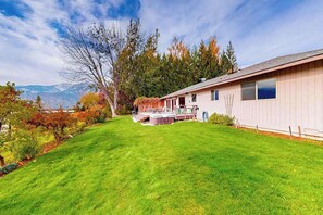 A single-story building with a covered patio area, a well-maintained lawn, and a mountainous backdrop. - Peaceful 3BR Lakeview - Hot Tub - Fireplace (Manson)
