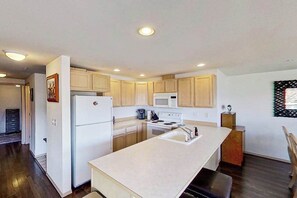 A kitchen with wooden cabinets, a white refrigerator, a microwave, a stove, and a sink.
