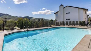 Piscina com vista para montanhas e um edifício ao fundo.