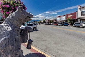 A street with parked cars, a building with a sign that reads 'World Pizza,' and a large sculpture of a horse's head.