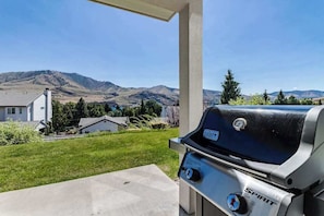 Ein Grill mit Spirit-Logo, draußen gelegen mit Blick auf einen Wohnbereich und Berge im Hintergrund.