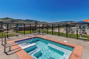 A swimming pool with a view of hills, a fenced deck area, and outdoor seating. - 1BR Lakefront 2nd-Floor - Balcony - Pool (Chelan)