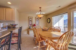 A dining area with a wooden table and chairs, a chandelier, and framed artwork on the walls.