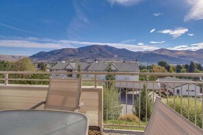 A balcony with a view of mountains and residential buildings. - Welcoming 2BR Lakeview - Balcony - Pool (Chelan)