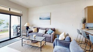 A modern living room with a sofa, armchairs, a coffee table, and a view of the outdoors. - 2BR Lakefront - Patio - Pool - Tennis - Dock (Chelan)