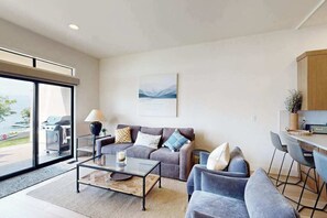 A modern living room with a sofa, armchairs, a coffee table, and a view of the outdoors. - 2BR Lakefront - Patio - Pool - Tennis - Dock (Chelan)