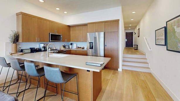 A modern kitchen with wooden cabinets, stainless steel appliances, and a central island with bar stools. - 2BR Lakefront - Patio - Pool - Tennis - Dock (Chelan)