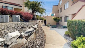 A residential building with a stone retaining wall, a pathway, and a well-maintained garden. - 2BR Lakefront - Patio - Pool - Tennis - Dock (Chelan)
