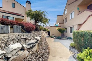 A residential building with a stone retaining wall, a pathway, and a well-maintained garden. - 2BR Lakefront - Patio - Pool - Tennis - Dock (Chelan)