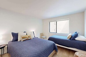 Quarto com duas camas, uma janela e uma mesa de cabeceira.