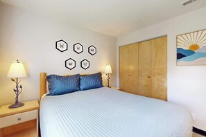 A bedroom with a bed, two bedside tables with lamps, a wardrobe, and wall art. - 2BR 1st-Floor - Icicle Village Resort Condo (Leavenworth)