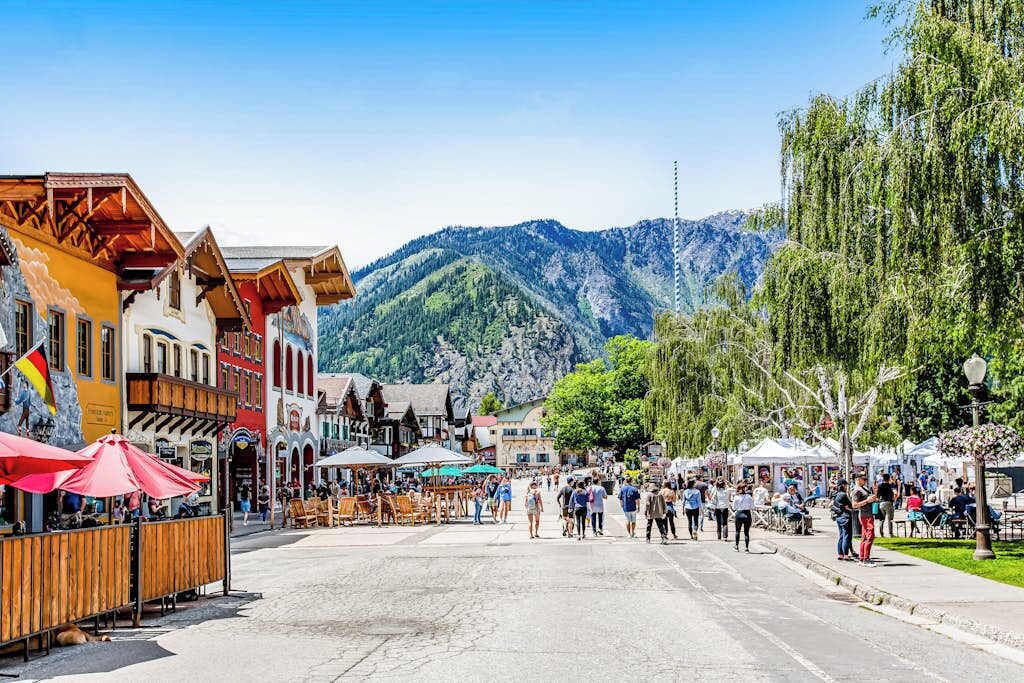 A town square with buildings, outdoor seating, and a mountain in the background.
