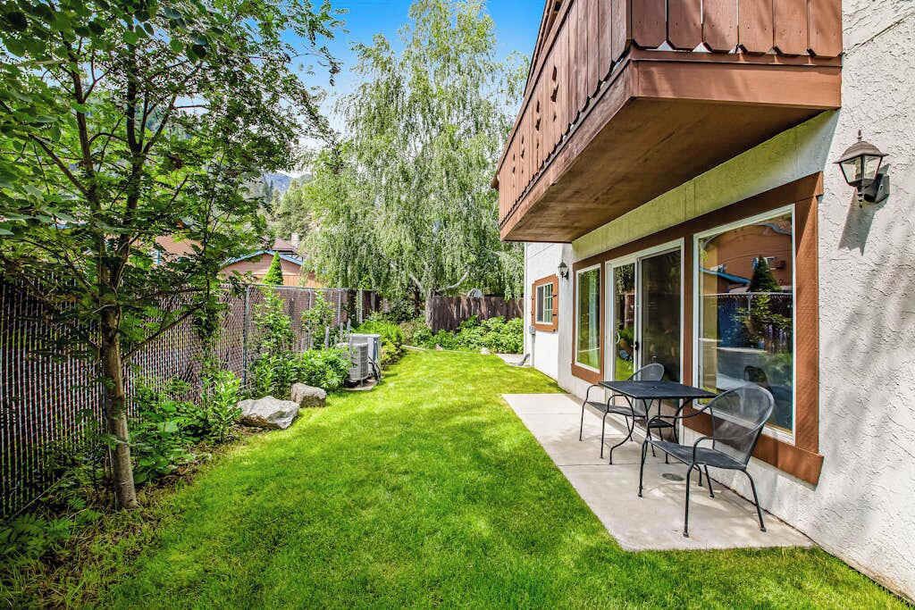A house with a well-maintained lawn, a patio with outdoor furniture, and a wooden balcony.