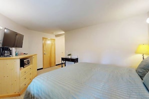 Ein Schlafzimmer mit Bett, Fernseher, Schreibtisch und Lampe.