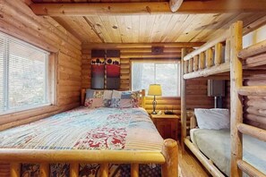 A log cabin room with a bed, a nightstand, a lamp, and a bunk bed. - 1BR Lakeview - WoodStove - Deck - Firepit - W&D (Leavenworth)