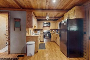 A kitchen with wooden cabinets, a black refrigerator, a microwave, and a stove. - 1BR Lakeview - WoodStove - Deck - Firepit - W&D (Leavenworth)