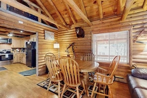 A wooden cabin interior with a dining area, kitchen, and a bear head decoration. - 1BR Lakeview - WoodStove - Deck - Firepit - W&D (Leavenworth)