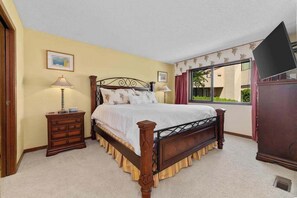 A bedroom with a bed, a dresser, a lamp, and a television. - 2BR Lakefront 2nd-Floor - Pool - Balcony (Chelan)