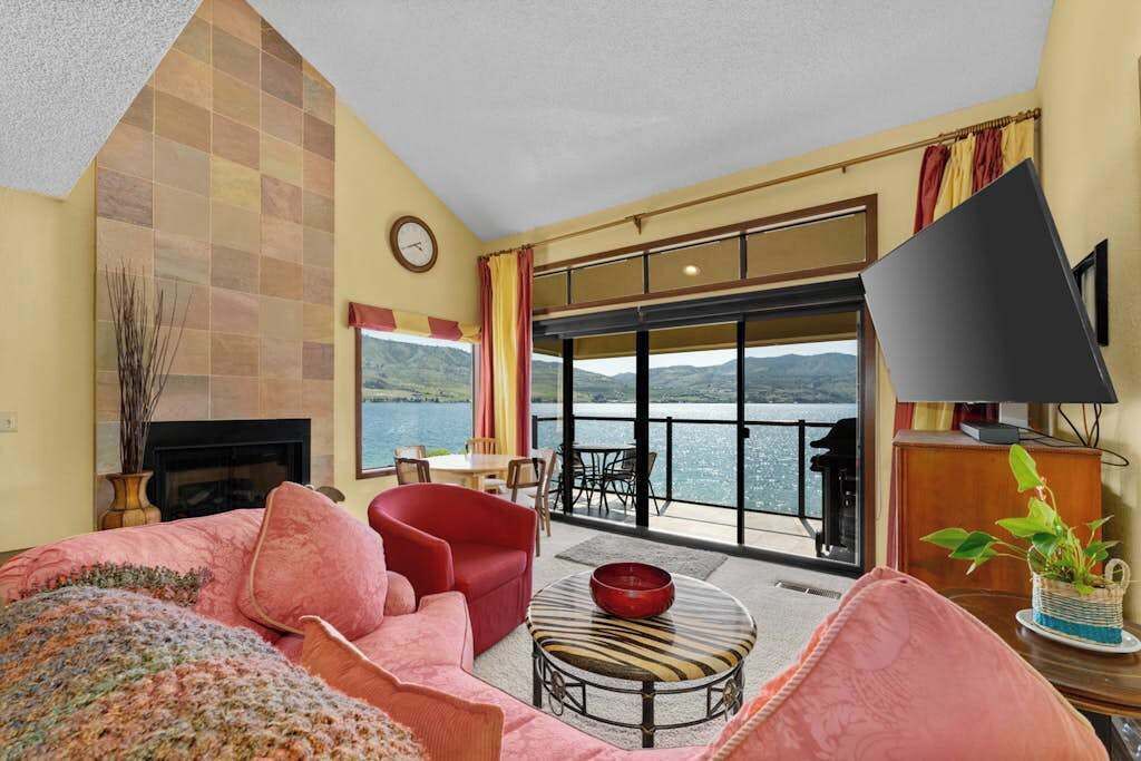Una sala de estar con chimenea, un sofá rojo, una mesa de centro y un televisor.