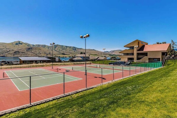 A tennis court with a building in the background. - 2BR Lakefront 2nd-Floor - Pool - Balcony (Chelan)
