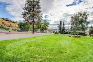 A well-maintained grassy area with a fence, trees, and a building in the background. - 4BR dog friendly waterfront home with shared pool (Orondo)