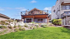 Een huis met twee verdiepingen, een houten terras en een balkon.