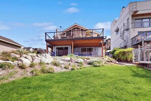 A two-story house with a wooden deck and a balcony. - 4BR dog friendly waterfront home with shared pool (Orondo)