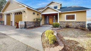 Ein zweigeschossiges Haus mit Steinuntergrund, Garage und Veranda.