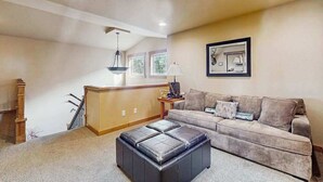 Ein Wohnzimmer mit einer Couch, einem Hocker und einer Holztreppe.