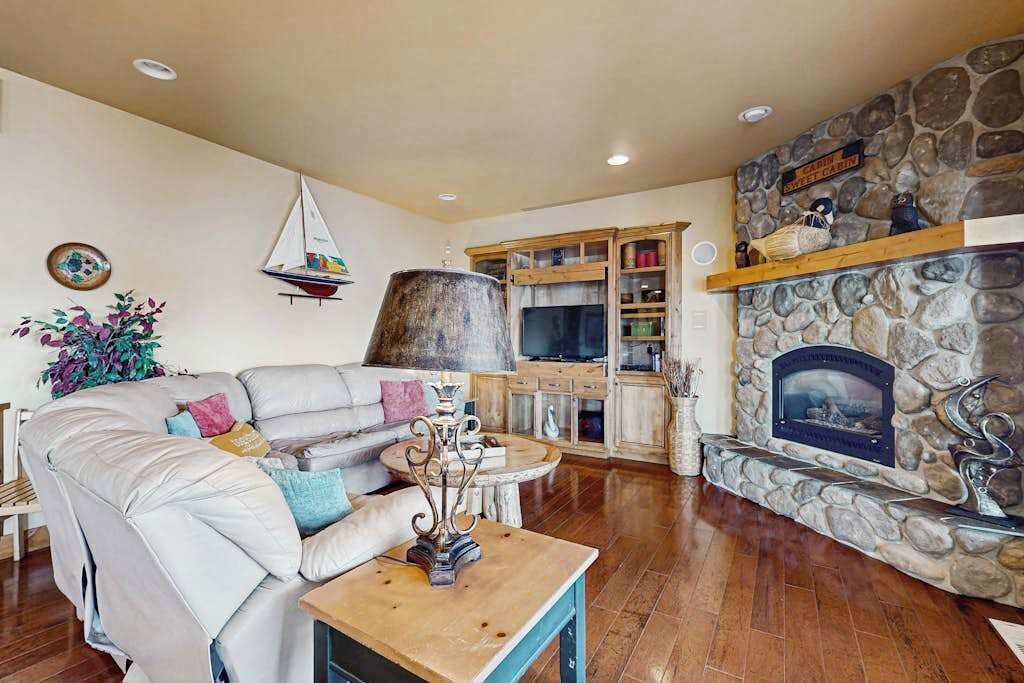 Una sala de estar con chimenea de piedra, un ventanal grande y un aparador de madera.