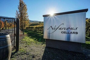 Une enseigne pour « Nefarious Cellars », avec un vignoble en arrière-plan.