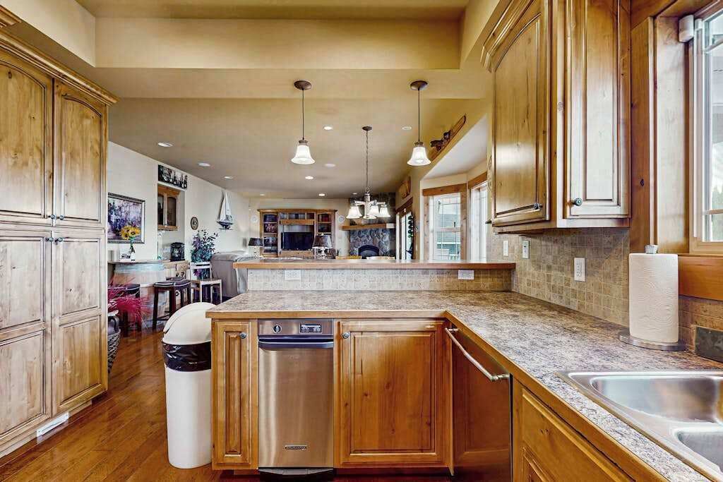 A spacious kitchen with wooden cabinets, a central island, stainless steel appliances, and pendant lighting.
