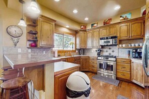 A kitchen with wooden cabinets, a marble countertop, a sink, a stove, and a refrigerator. - 4BR Lakeview - Fireplace - Deck - W&D (Chelan)
