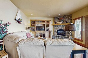 Un salon chaleureux avec une cheminée, un téléviseur et une décoration sur le thème de la voile.