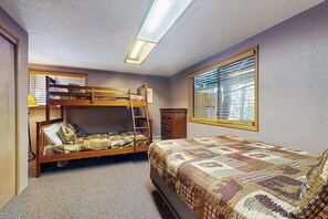 Ein Zimmer mit Etagenbetten, einem Schminktisch und einem Fenster mit Jalousien, sowie einer Deckenleuchte.
