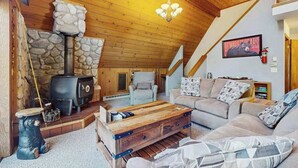 Una sala de estar acogedora con chimenea de piedra, un conjunto de sofá y una mesa de centro de madera.