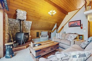 Ein gemütliches Wohnzimmer mit Kamin aus Stein, einer Sofagarnitur und einem Holztisch.