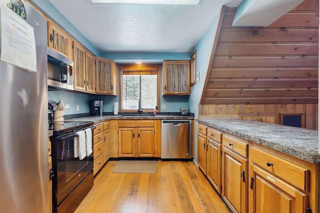 Una cocina con gabinetes de madera, un refrigerador de acero inoxidable y un lavavajillas.